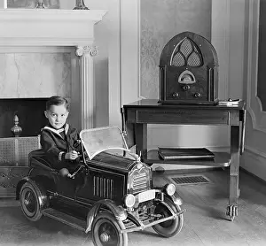 Cabinet Prints: Little boy in his toy automobile next to a state of the art Atwater Kent Radio
