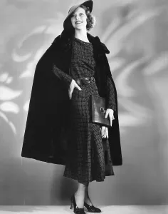 Cape Prints: Loretta Young in Alaska seal cape worn over brown woolen dress designed by Nina Foley