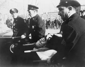 Assassination Prints: Malcolm X (1925-1965), on stretcher carried by New York policemen following his assassination at rally in a Harlem