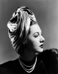 Glamorous Prints: Maria Montez, modeling a Lilly Dache turban of pink, blue and green satin, 1945