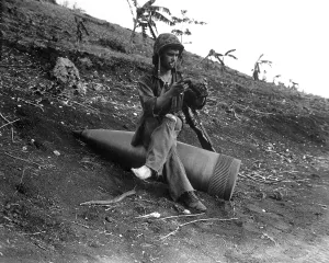 Foot Prints: A Marine sits on an 16-inch naval shell to shake a three-days of sand from his boots