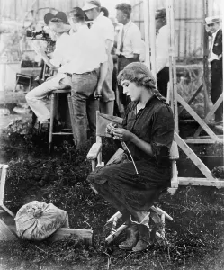 Pickford Prints: Mary Pickford on a movie set knitting for Red Cross, ca. 1920