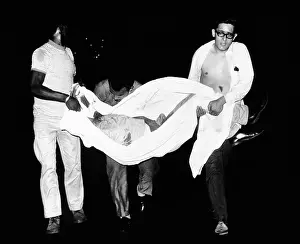 Urban Poverty Prints: Three men carry body of a youth who died after apparently falling from a rooftop during third night of civil disorder