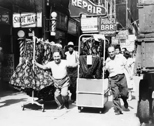 Images Dated 8th May 2008: Men pulling racks of clothing on busy sidewalk in Garment District