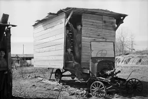 Shack Prints: Three men stand in the entry of their shack home built on an old truck chassis