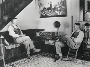 Communication Prints: Middle aged farmer and his adult son listening to the radio in their comfortable home