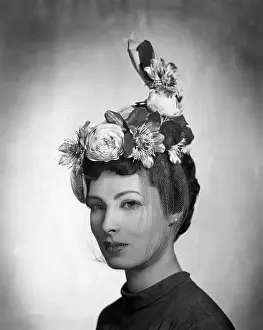 Flowers Prints: A model wearing a hat by Lilly Dache made of gray linen straw with yellow roses and passion flowers