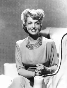 Natalie Prints: Natalie Schafer, modeling a necklace made of beige fringe and gold beads, 1944