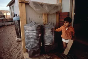 Trash Can Prints: Native American reservation. A young boy in fornt of his home