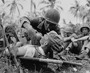 Palm Trees Prints: US Navy corpsman gives a drink to wounded Marine on Guam