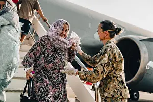 Italy Prints: US Navy Master Chief Anna Wood assists an Afghan evacuee upon arrival at the Italian Air Force Base