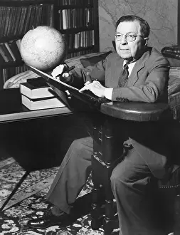 Bookshelves Prints: NBC Radio commentator Rupert Hughes at his unique writing chair'. May 1943