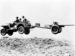 Jeep Prints: The new jeep in mid-air as it pulls a small artillery piece ca. 1941