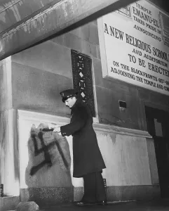 Rs4wn Prints: New York City policeman inspects a black swastika painted on the entrance wall of Temple Emanu-el