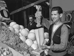 Grapes Prints: New York City, Pushcart vendor bagging grapes at his produce stand, photograph, 1940