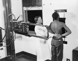Tuberculosis Prints: Nurse placing patient in the correct position for taking a chest X-ray for use in the diagnosis of tuberculosis