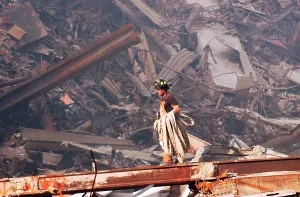 Skyscraper Prints: NYC Fire fighter carries a fire hose over smouldering fires and wreckage at Ground Zero