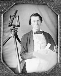Tripod Prints: Occupational portrait of an unidentified surveyor with a transit on a tripod and holding dividers and a map