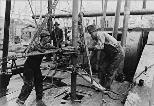 Extraction Prints: Oil roughnecks screw one piece of drill pipe to another piece with a heavy pipe wrench