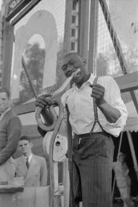 Sideshow Prints: One-legged Geek biting the head of a snake at a sideshow, Louisiana State Fair, 1938