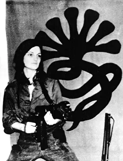 Hearst Prints: Patricia Hearst with weapon posing in front of SLA emblem