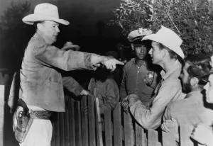 December Prints: Police chief instructs officers and young men on the other side of a fence