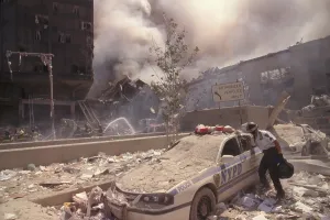 Skyscraper Prints: Policeman reaching into a debris covered police car after 9-11 terrorist attack in NYC