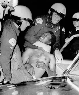 Riot Prints: Policemen force a man into a police car during the riots in Watts