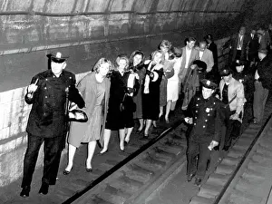 Tracks Prints: Policemen lead commuters through a subway tunnel