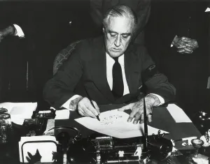 President Franklin Roosevelt signing the declaration of war against Japan. He wears a black armband in mourning for his recently deceased mother. Dec. 8, 1941. (BSLOC_2013_11_153)