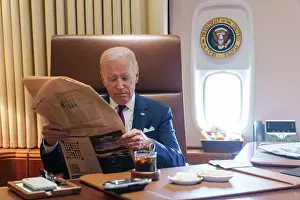 Reading Newspaper Prints: President Joe Biden reads a newspaper aboard Air Force One