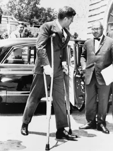 Crutches Prints: President John F. Kennedy on crutches accompanied by White House Press Secretary Andrew T