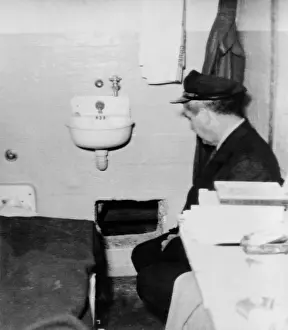 Islands Prints: Prison guard sits inside the Alcatraz cell with a hole in the wall through which one of the three prisoners Frank Lee