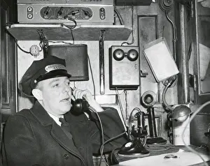 Conductor Prints: Railroad conductor uses an on board telephone to communicate with other parts of the train