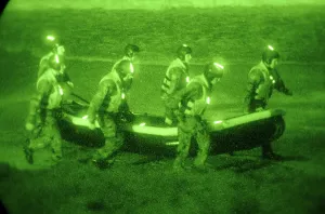 Commandos Prints: US Sailors assigned to Basic Underwater Demolition/SEAL training class carry an inflatable boat toward the surf in San