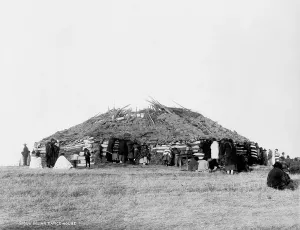 Roof Prints: Sioux Indian dance house, log building with sod roof and American Indians outside