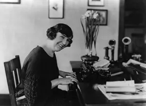 Skilled Labor Prints: Smiling woman office worker seated at typewriter, in 1923. (BSLOC_2015_16_220)