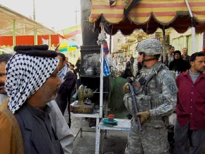 Iraq Prints: US soldier patrols the streets of Martyrs Market as local nationals shop in Mahmudiyah Iraq a Sunni Iraqi city south of