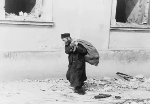 Polish Prints: A solitary Jewish man carrying a sack walking past bomb damaged buildings in Poland in the early days of World War II