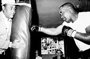 Louis Prints: Sonny Liston working out on the heavy bag while Joe Louis holds it