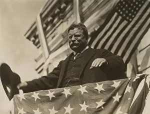 Candidate Prints: Surrounded by flags and bunting, Theodore Roosevelt looks out from a speakers platform