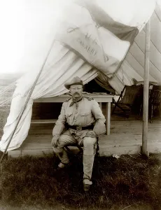 Camping Prints: Theodore Roosevelt, seated at entrance to tent. ca 1898