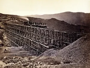 Images Dated 31st October 2008: Trestle work. Central Pacific Railroad construction workers standing on railroad flatcars being pushed by locomotive