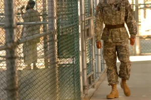 Candid Occupational Portraits Prints: A U.S. Army Soldier stands guard as a detainee spends time in the exercise yard outside Camp Five at Guantanamo Bay