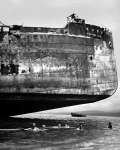 Italian American Prints: U.S. Coast Guardsmen swim near the wrecked Japanese transport, Kinuga Maru at Guadalcanal