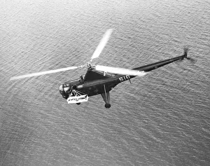 Korea Prints: U.S. H-5G helicopter's flying over water with a patient in an outboard litter during the Korean War