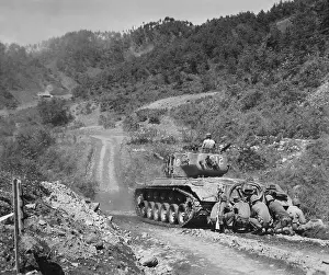 South Korea Prints: U.S. Marine infantrymen take cover behind a tank while it fires on Communist troops ahead