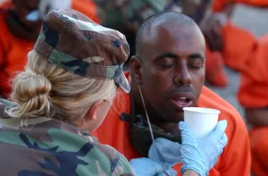 Candid Occupational Portraits Prints: U.S. Military Police woman provides water to a thirsty detainee as they arrive at Camp X-Ray at Guantanamo Bay Naval