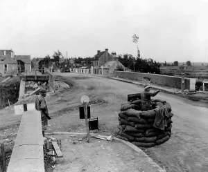 Guard Prints: U.S. MP controls traffic on a bridge at Carentan