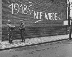 Engineers Prints: U.S. Ninth Army signalmen repair wires near German graffiti in the Netherlands